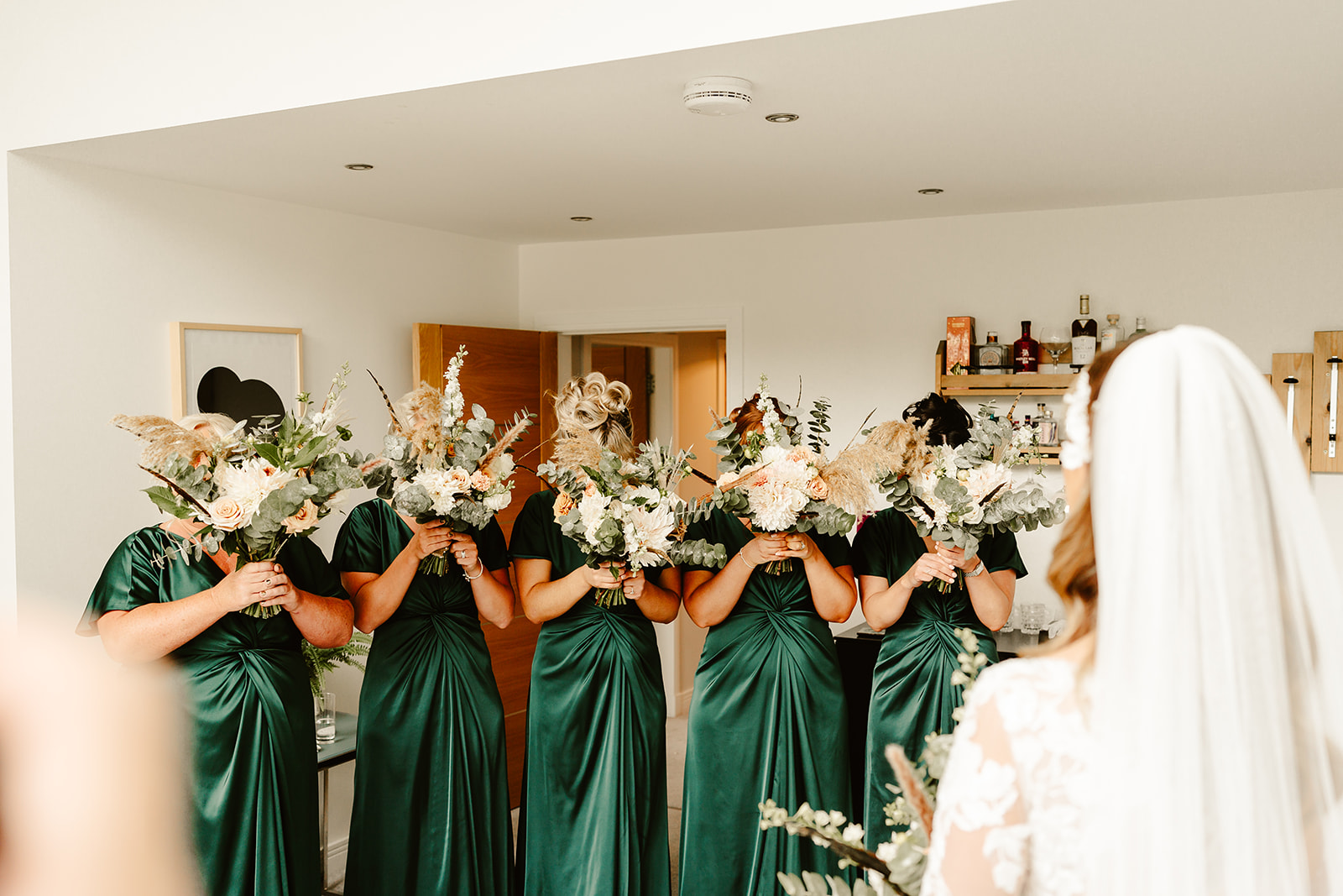 bridesmaids hide their faces behind flowers before seeing the bride