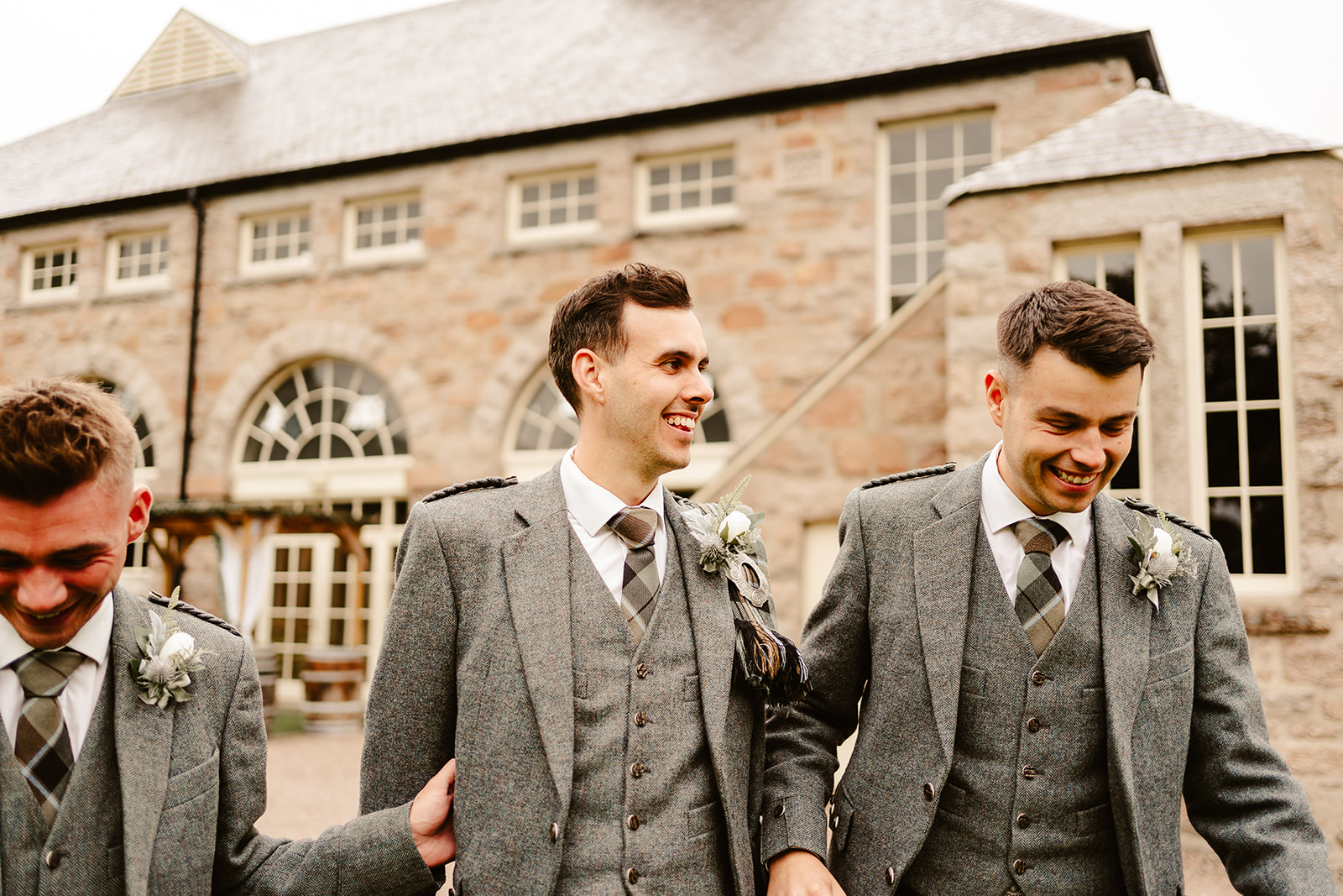 groom and two groomsmen walk in front of coos cathedral wedding venue