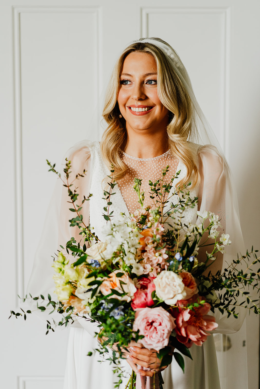 bride is holding her bouquet as she stands and smiles before her Scottish wedding ceremony