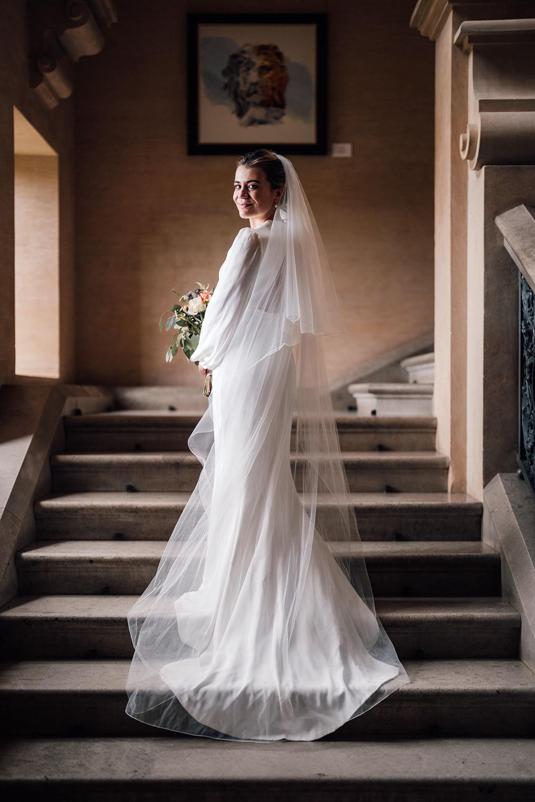 bride on the stairs in window light at Harlaxton Manor