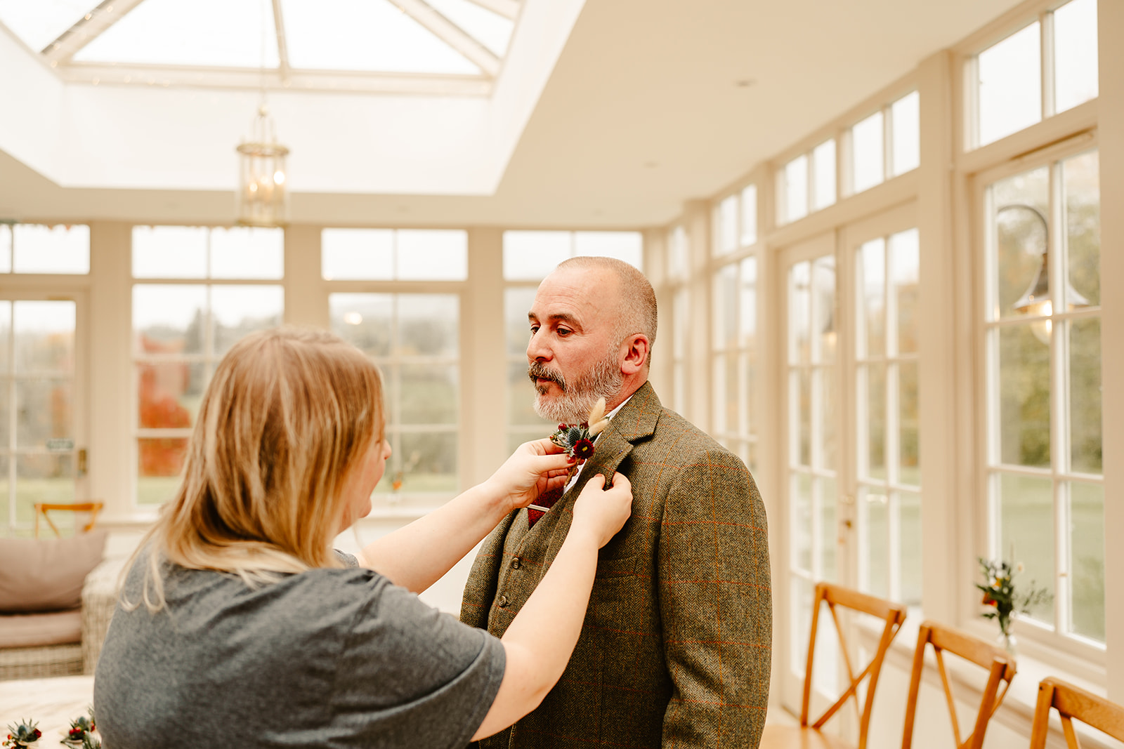a woman is putting a button hole on the groom at ballogie house