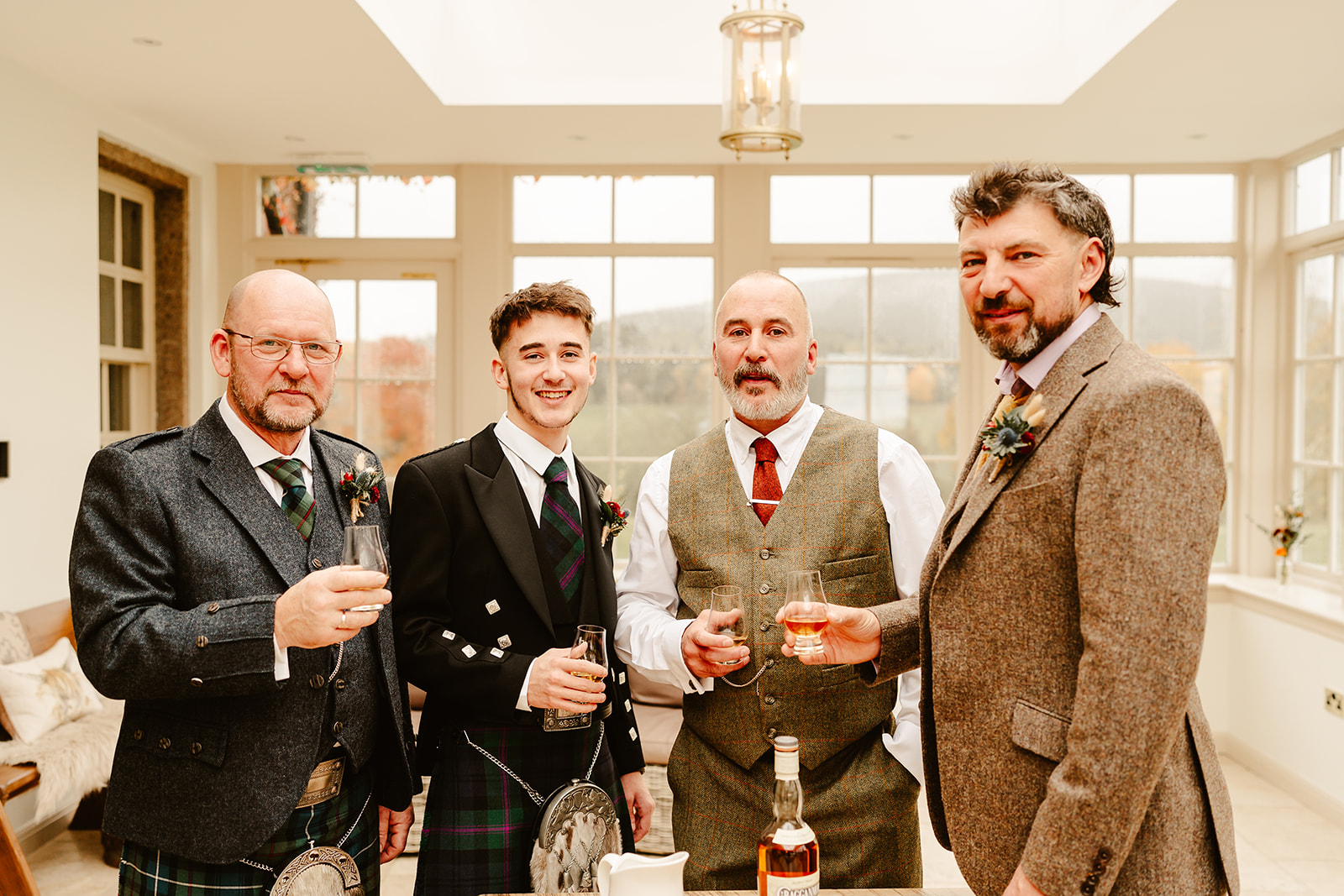 groom and best men drink whisky at ballogie house during scottish wedding 