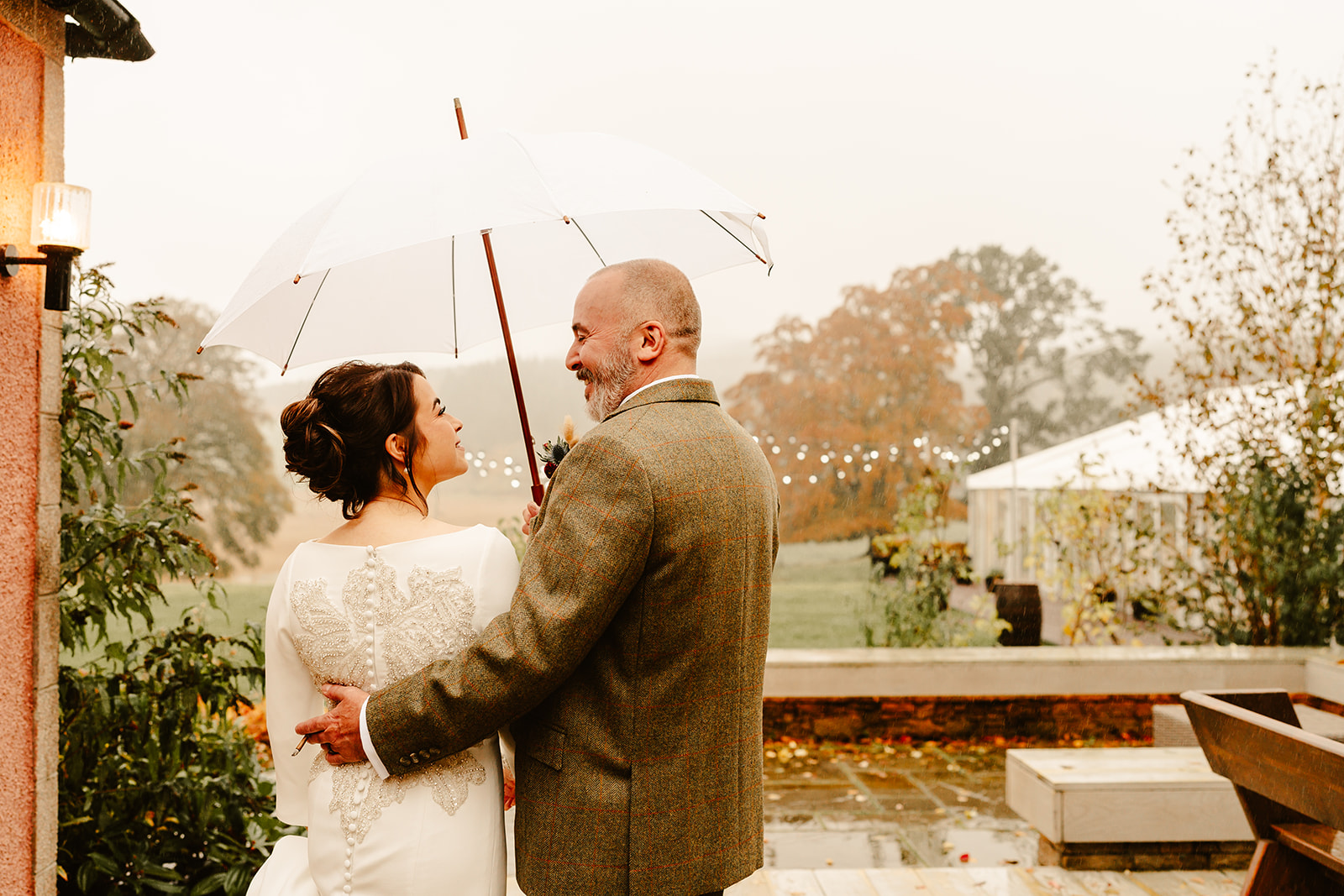 A couple pose under umbrella during their autumn wedding at ballogie House