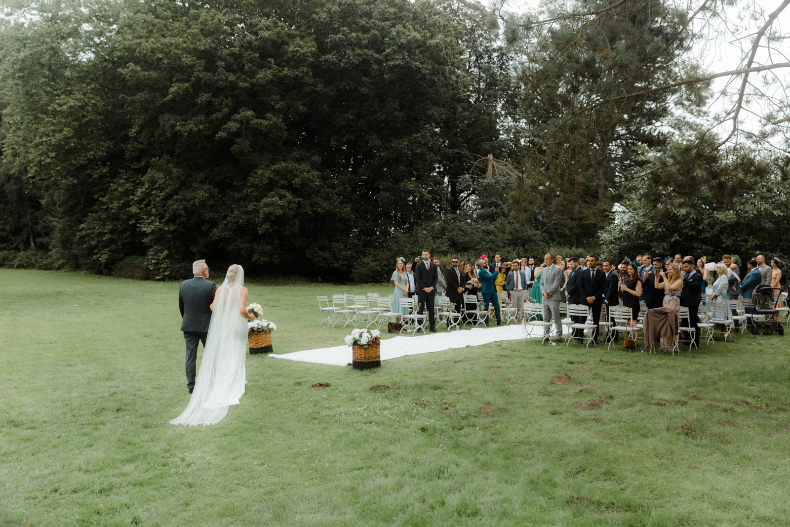 Die Braut geht mit ihrem Vater zur Trauung bei ihrer Hochzeit auf dem Herrenhaus Gut Bliestorf.