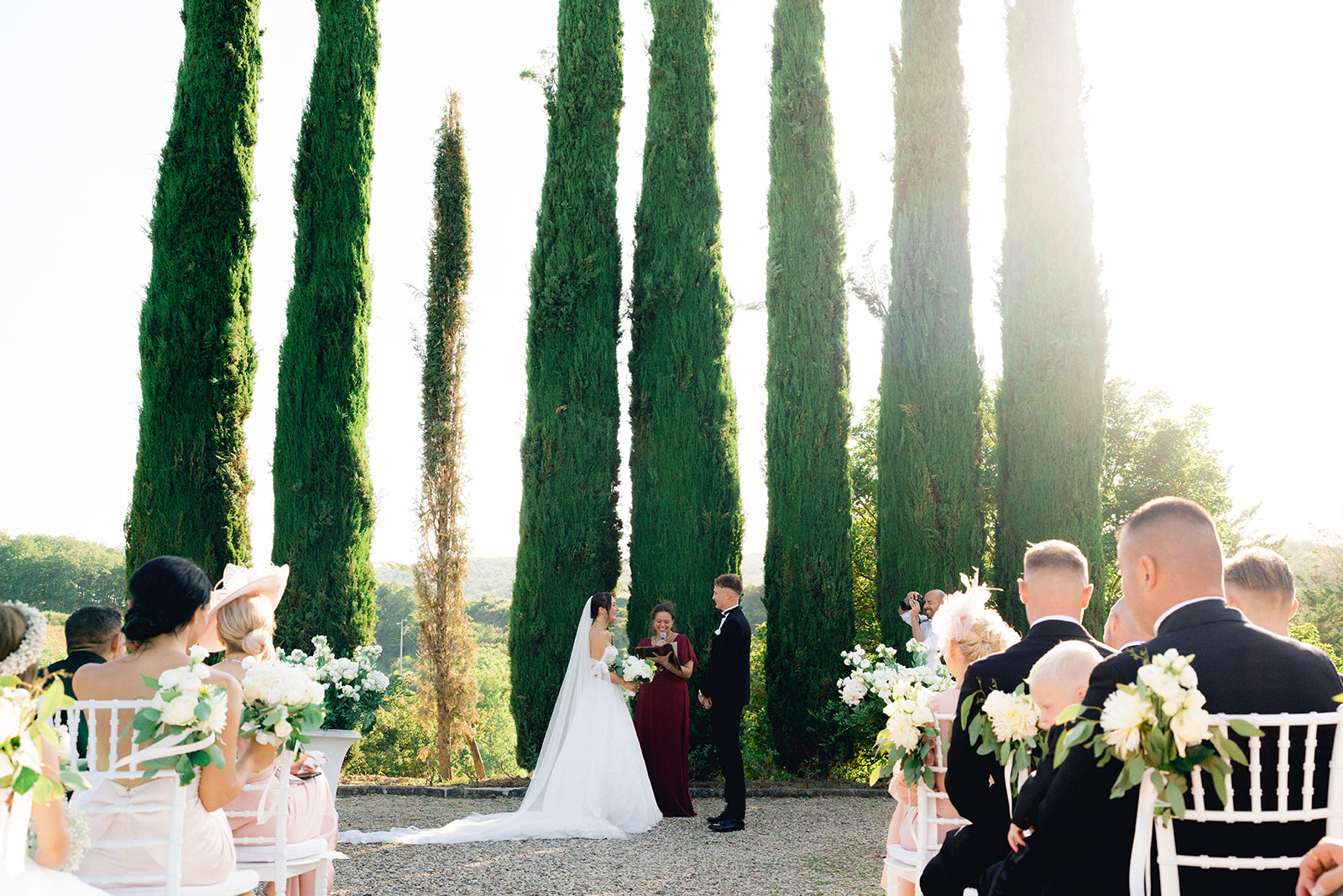 The bride and groom exchange vows under the iconic cypress trees in the garden of Villa La Selva