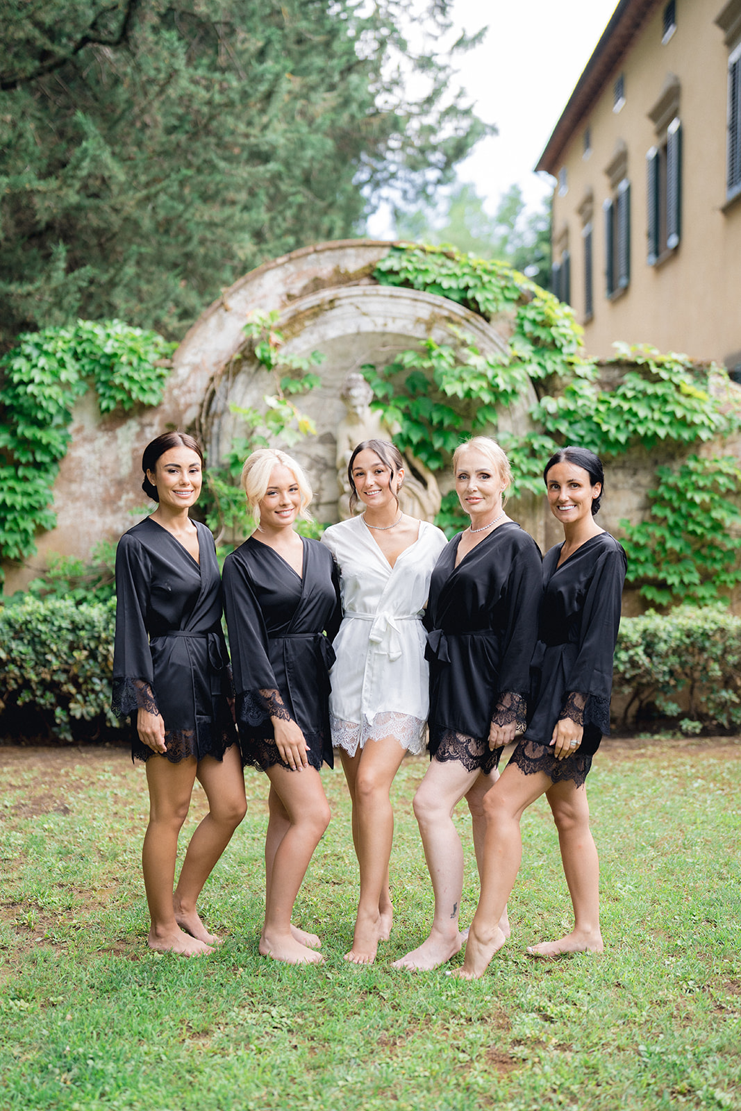 The bride and her bridesmaids in robes on the lawn of Villa La Selva Wine Resort