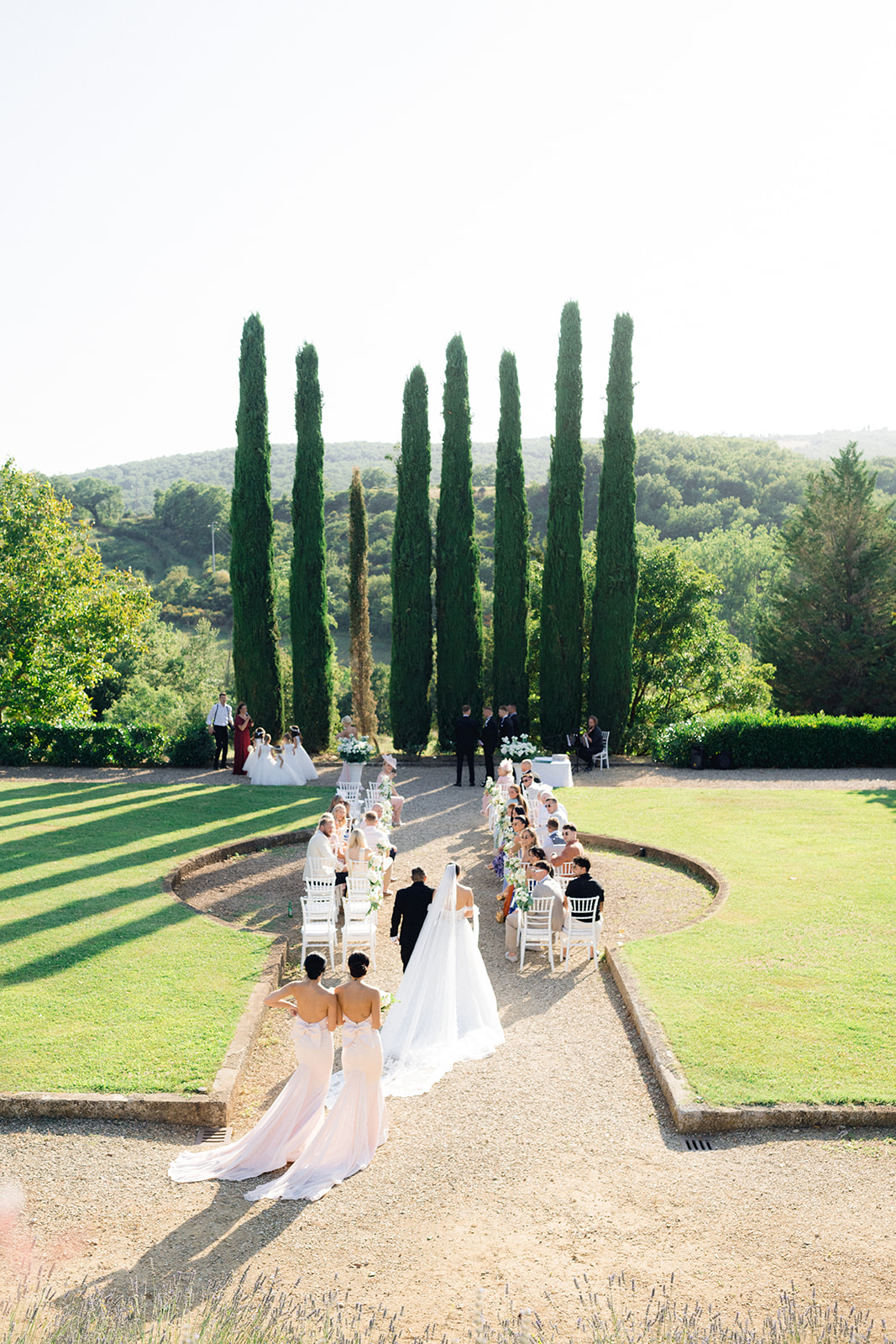 the bride walking down the aisle of the garden of Villa la Selva Wine Resort