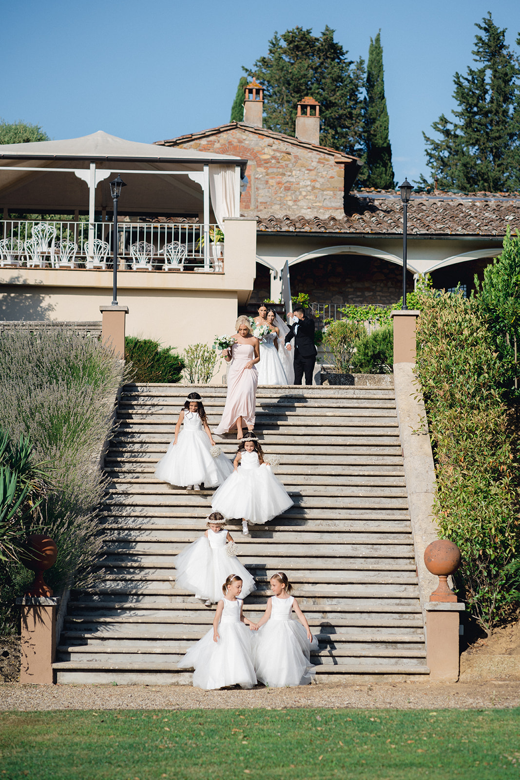 the flower girls are walking down the stairs of the garden of Villa la Selva