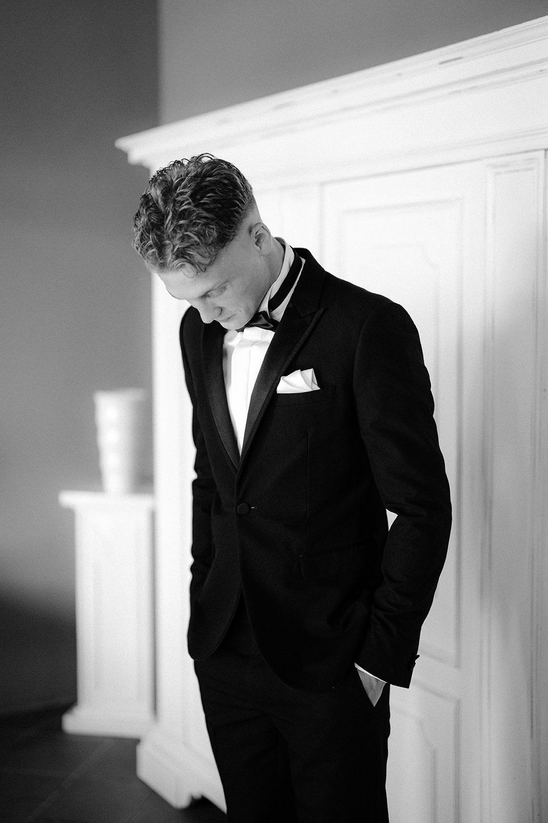 The groom checks his outfit after putting on the tuxedo for his wedding