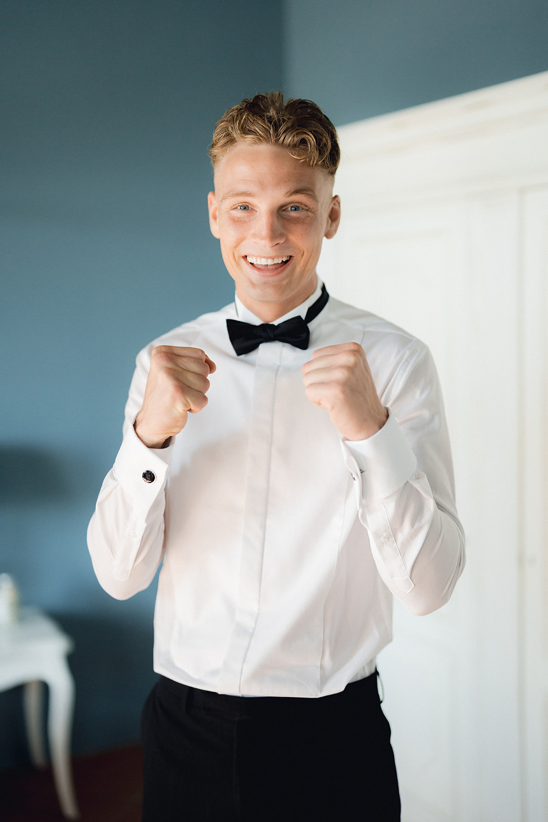 The groom in a shirt and bow tie, smiling