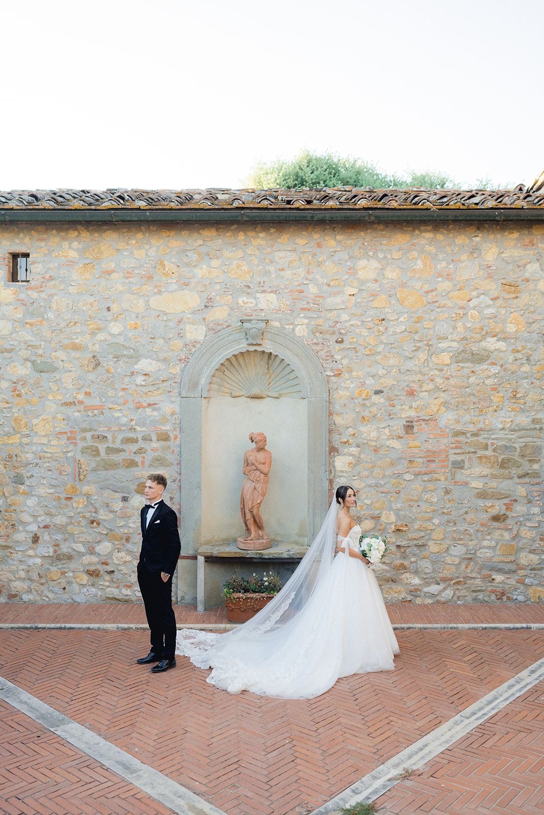 The newlyweds pose next to a statue in the gardens of Villa La Selva