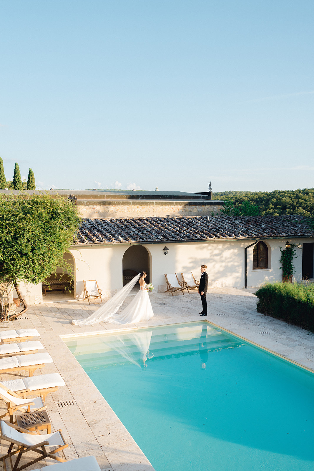 The newlyweds walk near the edge of the pool at Villa La Selva in Arezzo