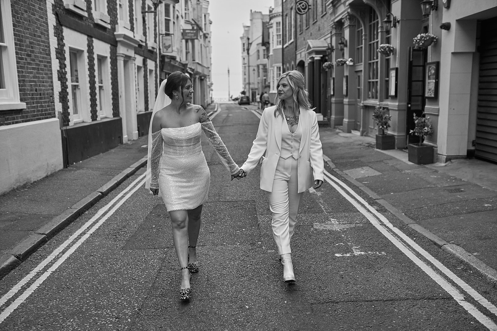 brides holding hands while walking in the street