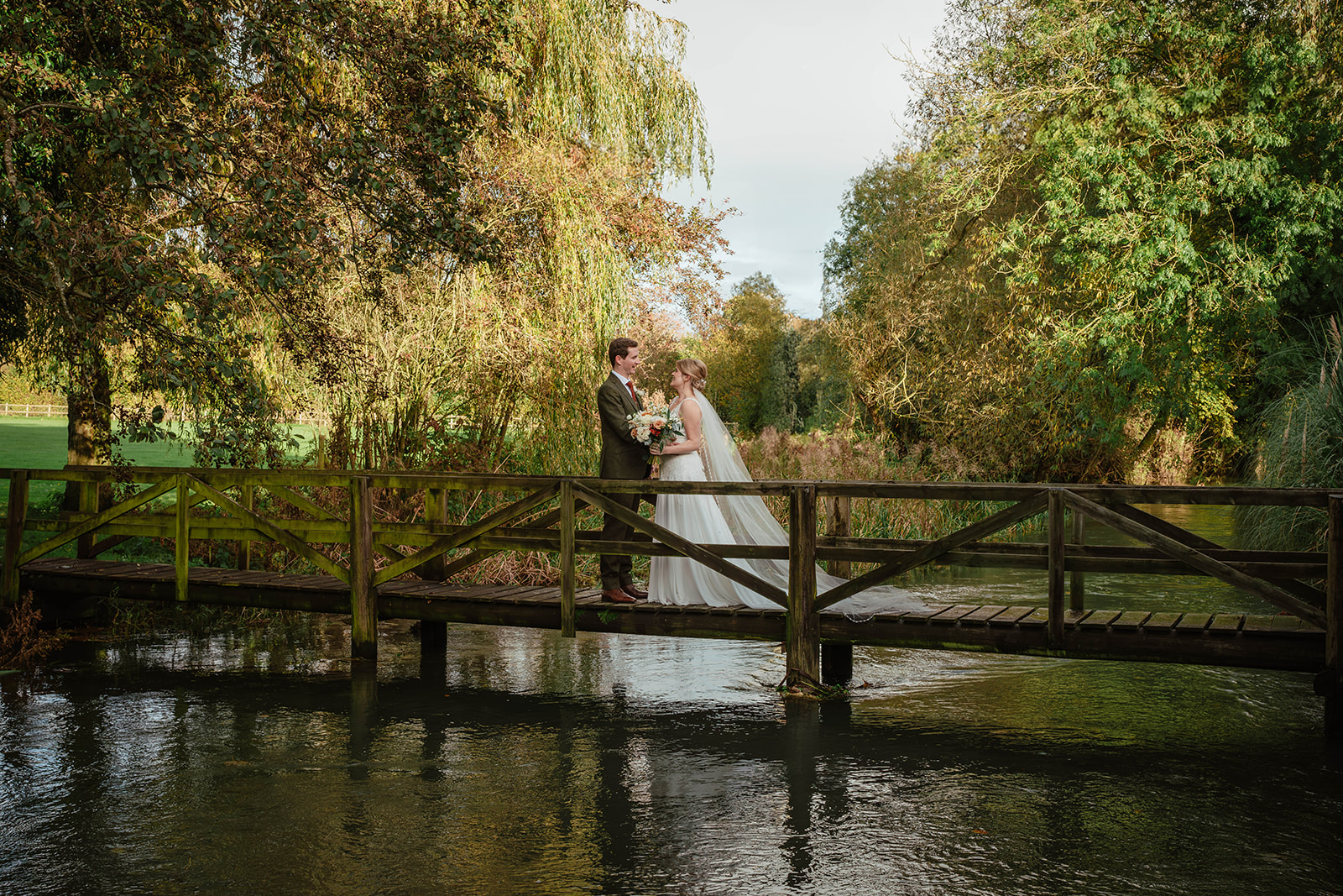 bride and groom on bridge on river Zara Davis Photography Wild Thyme and Honey Cirencester Cotswolds Gloucestershire