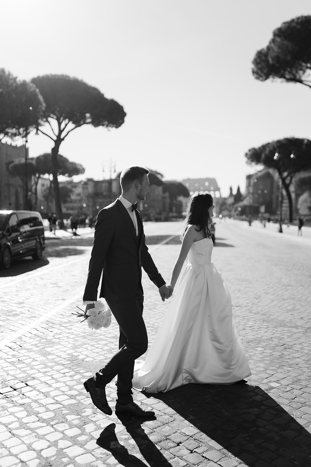 After wedding photoshoot in Rome. Couple walking via dei fori imperiali photographed by Clara Buchberger.
