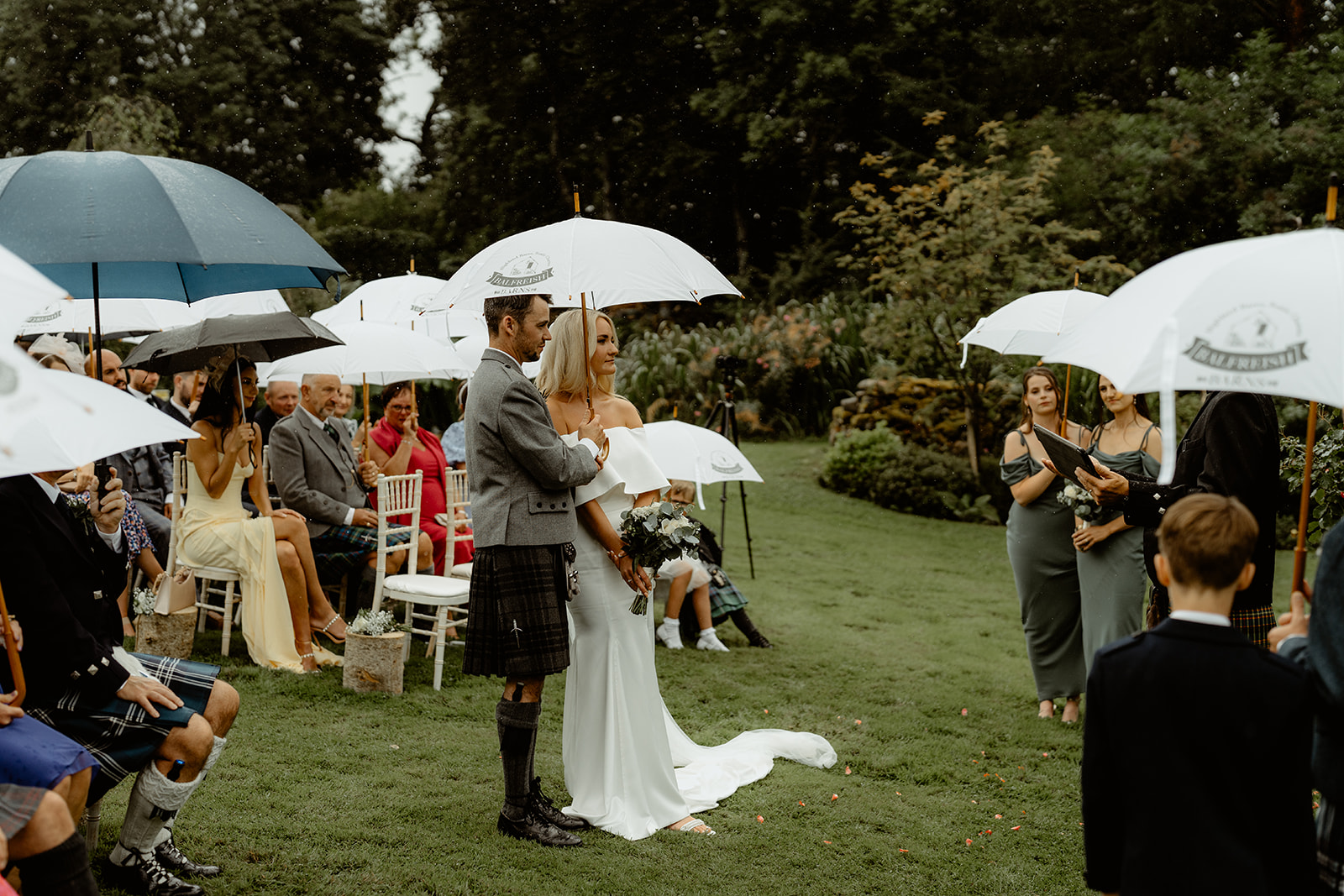 Wedding ceremony in the rain with everyone taking shelter underneath umbrellas
