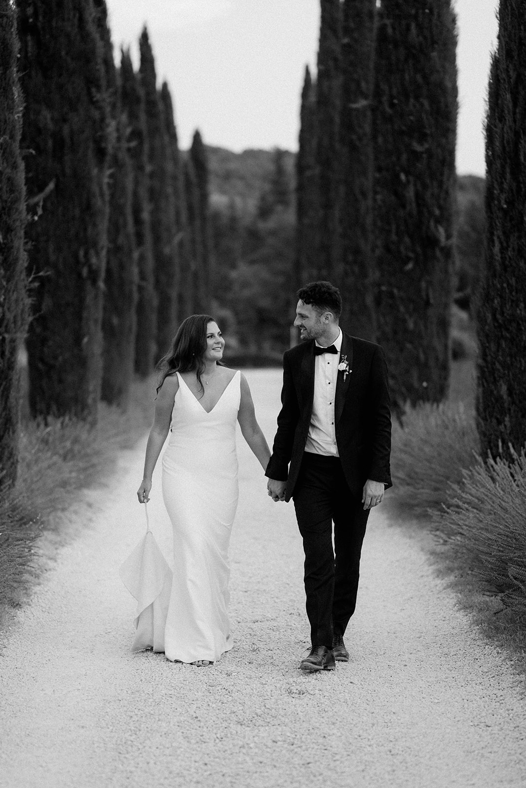 couple walking down tree lined road in provence at Le Mas Des Costes