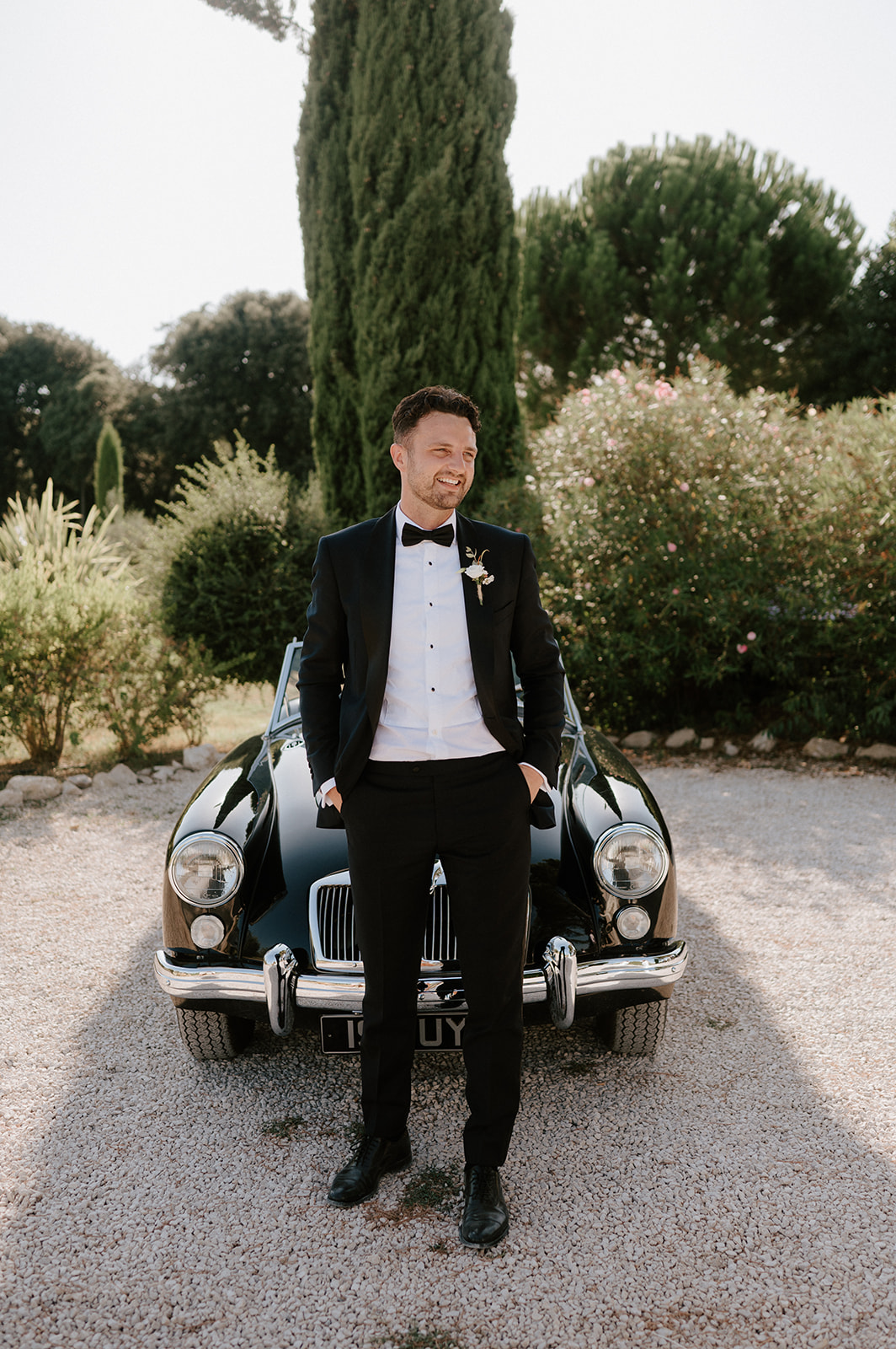 groom standing in front of vintage mg classic car at Le Mas Des Costes in provence