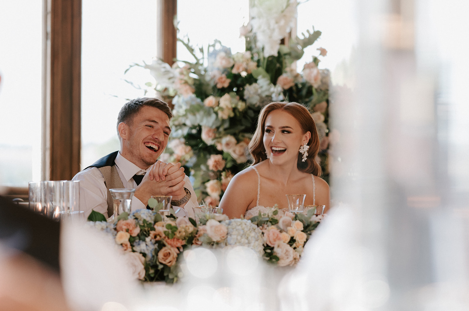bride and groom laughing during wedding speeches