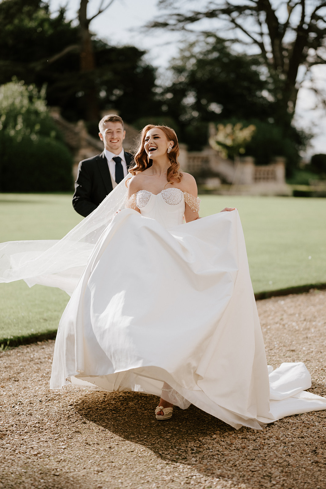 bride and groom laughing whilst walking at harlaxton manor