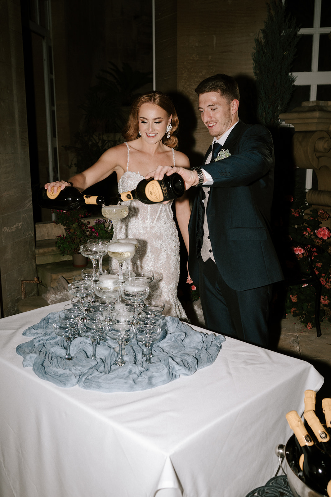 bride and groom pouring Prosecco into champagne tower at harlaxton manor