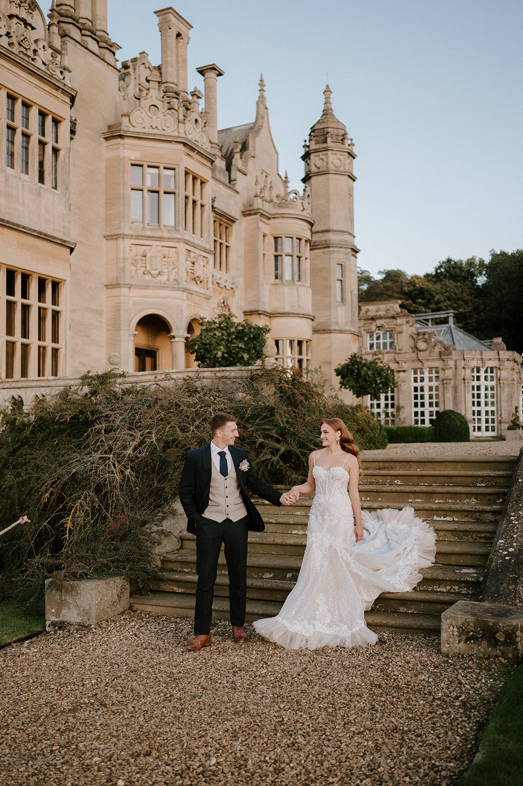 bride and groom walking downs steps at harlaxton manor