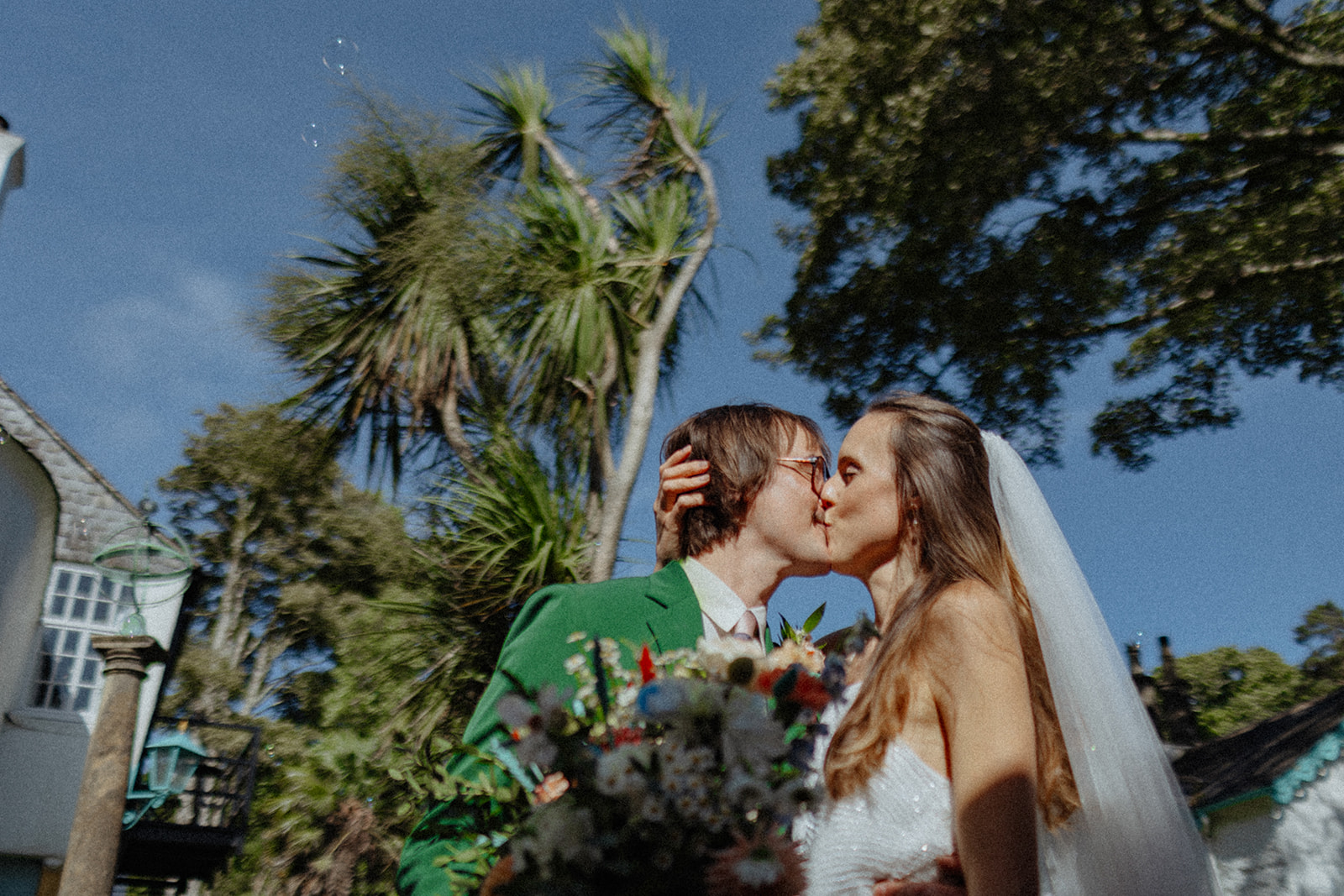 Bride and groom kissing against colourful background at Frances quinn wedding in wales