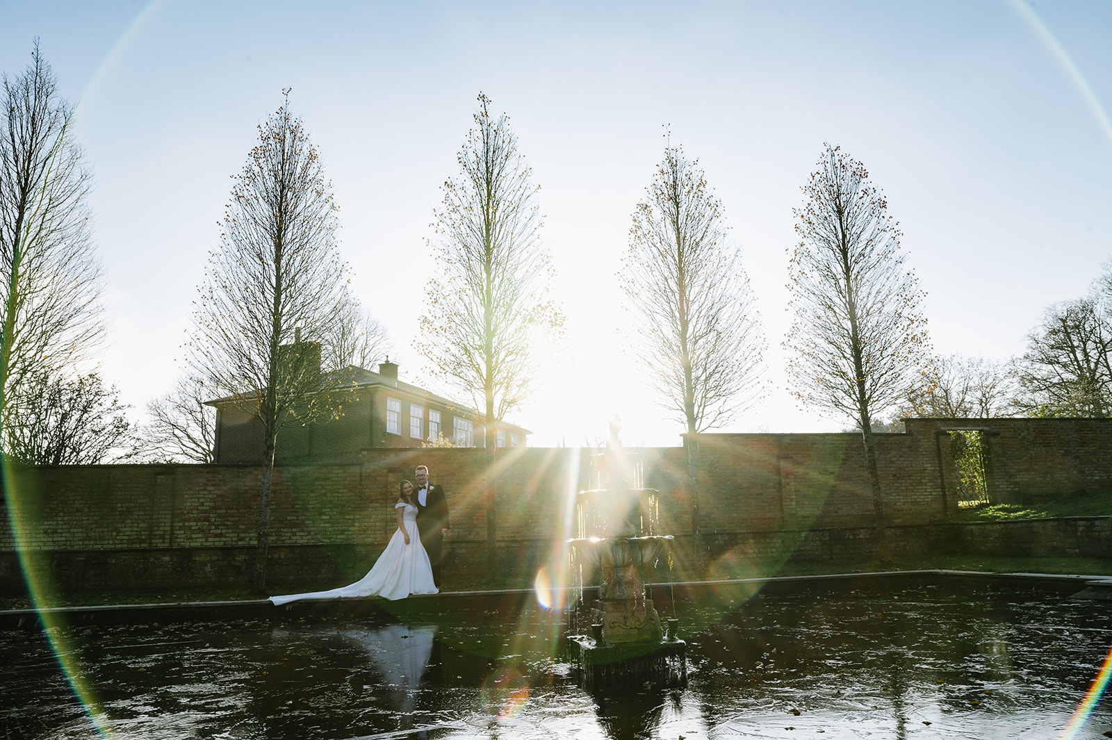 the bride and groom walk next to the frozen pond at Bourton Hall