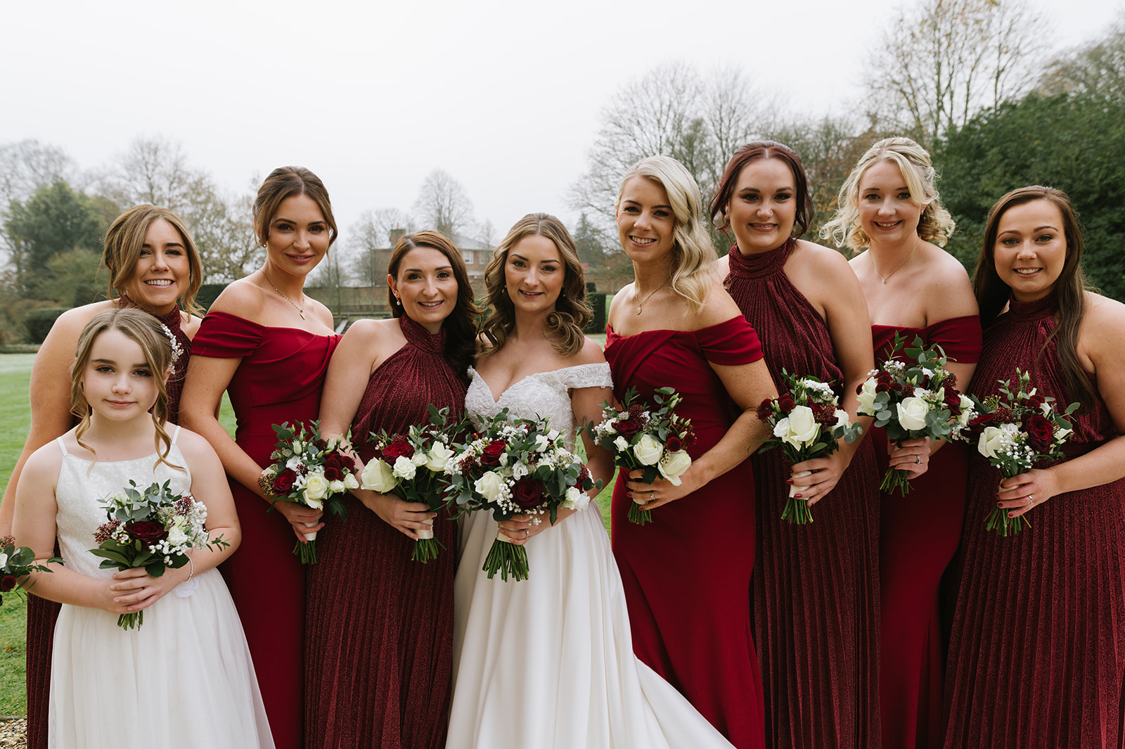 the bride with her bridesmaids in red sparkly dresses outside on a wintery day