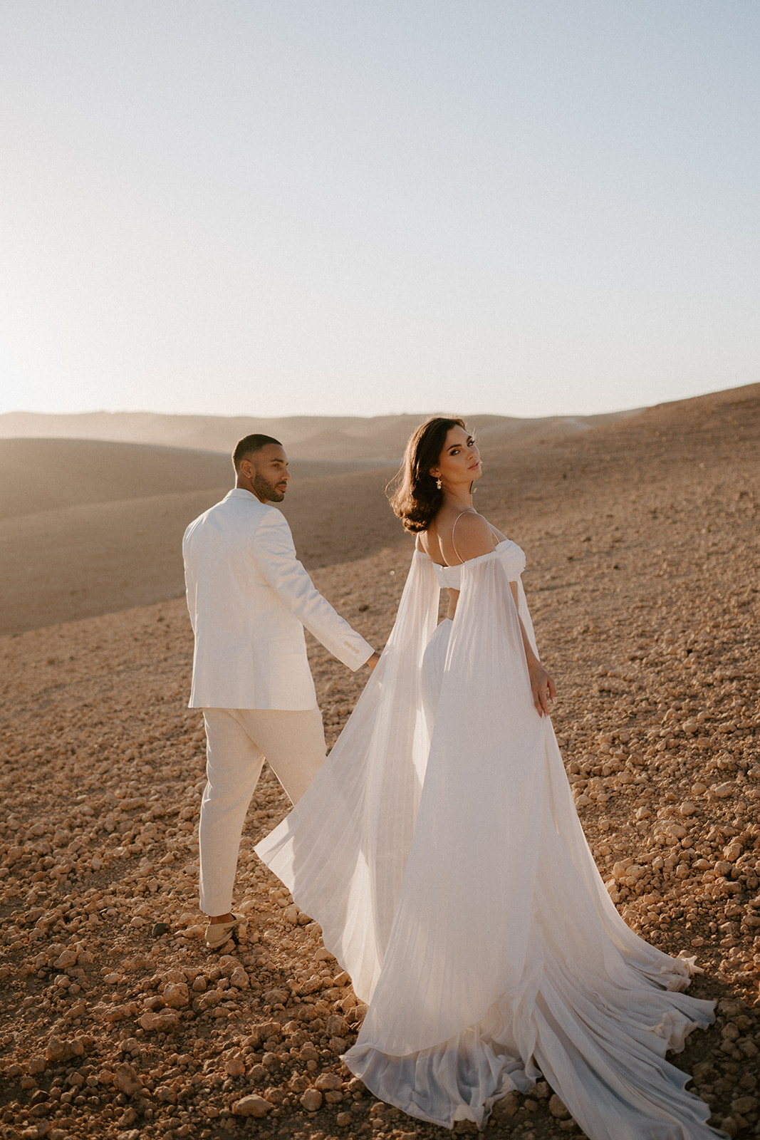 bride and groom walking on sand dunes at agafay desert in marrakesh