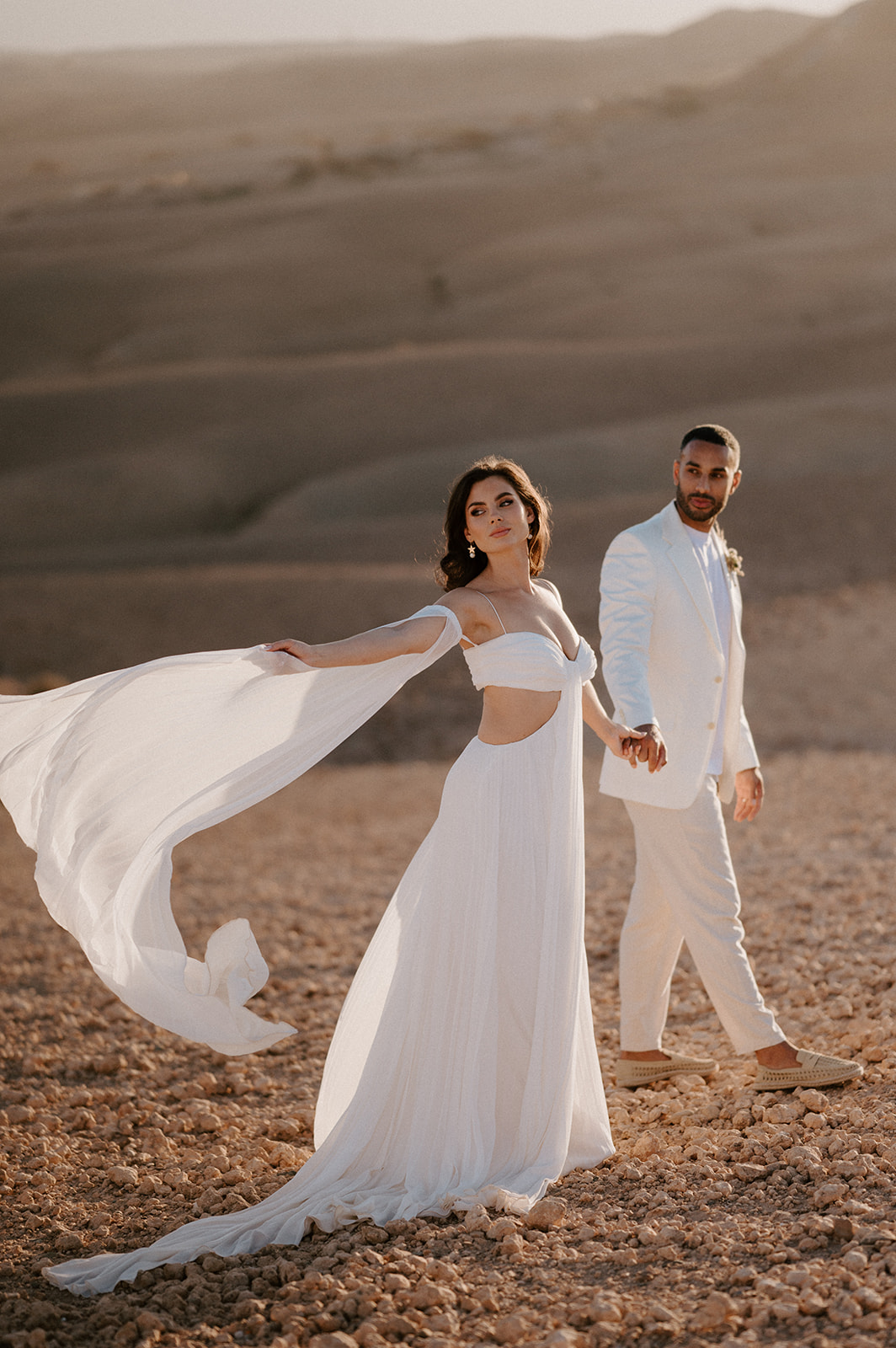 bride and groom walking on sand dunes at agafay desert in marrakesh