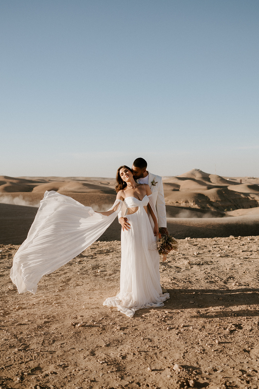 bride with white wedding dress standing with groom in agafay desert wedding elopement 