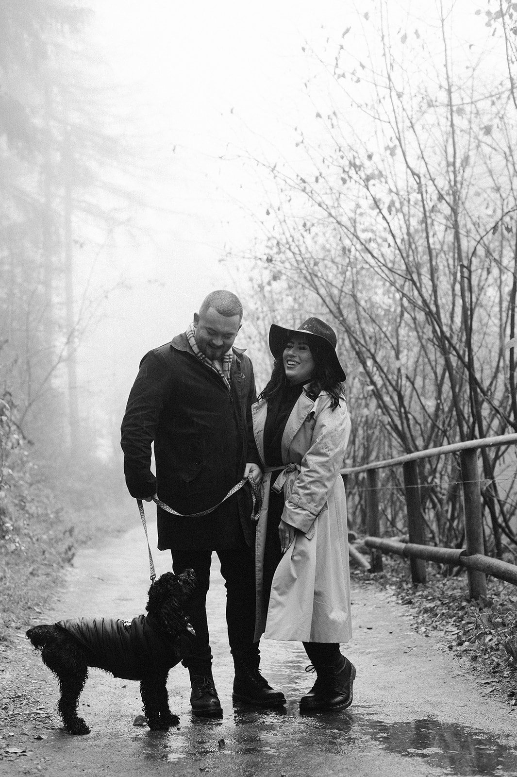 black and white photo of a couple in the rain with their dog