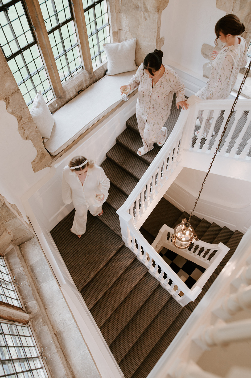 bride and bridesmaids walking down stairs at butley priory wearing pjs