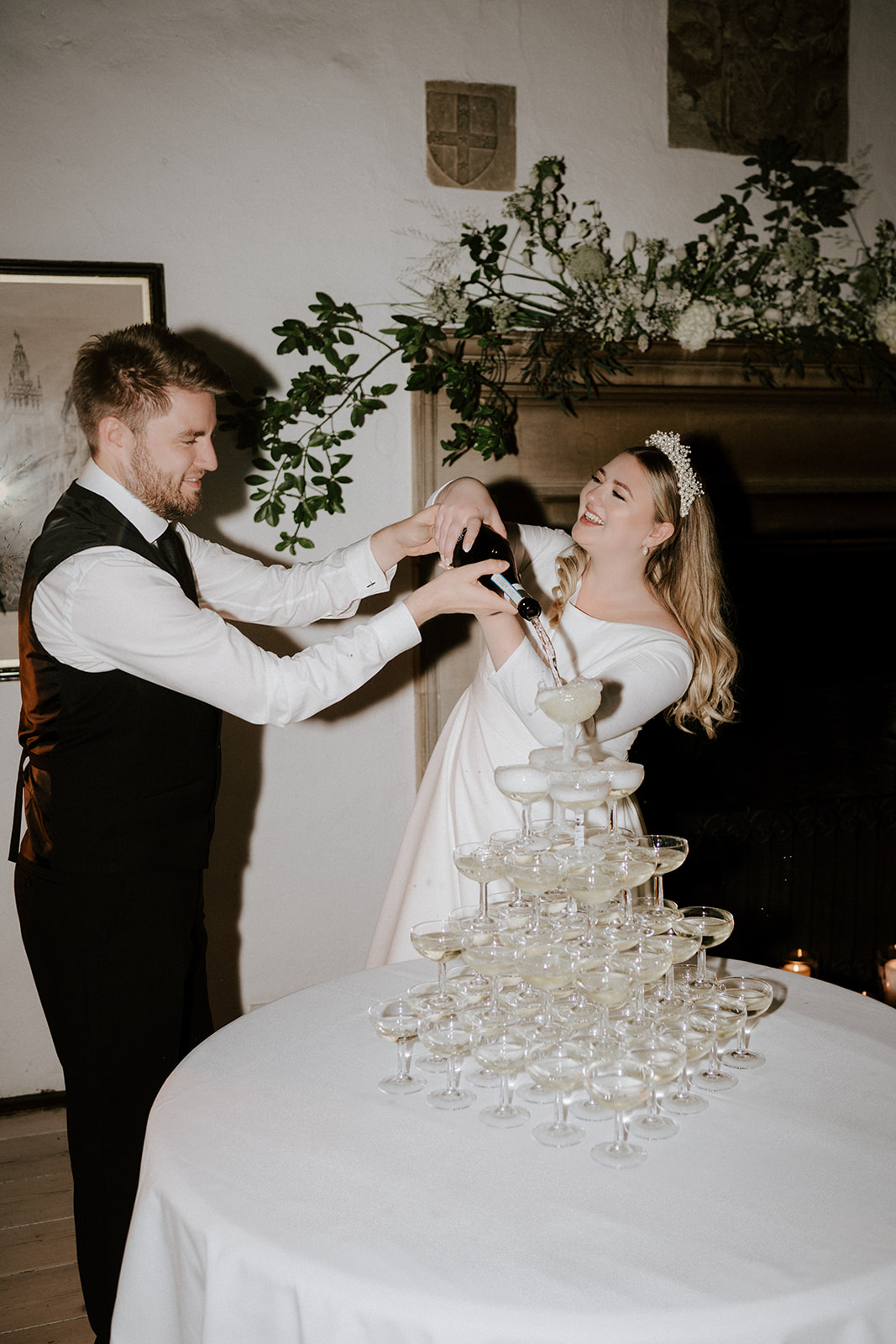 bride and groom pouring champagne in great hall at butley priory