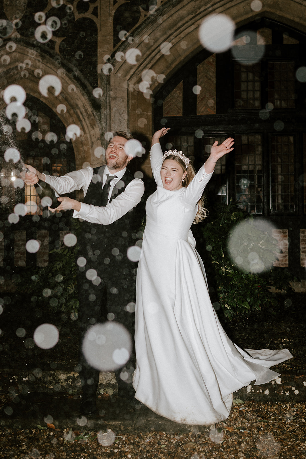 bride and groom spraying champagne outside butley priory