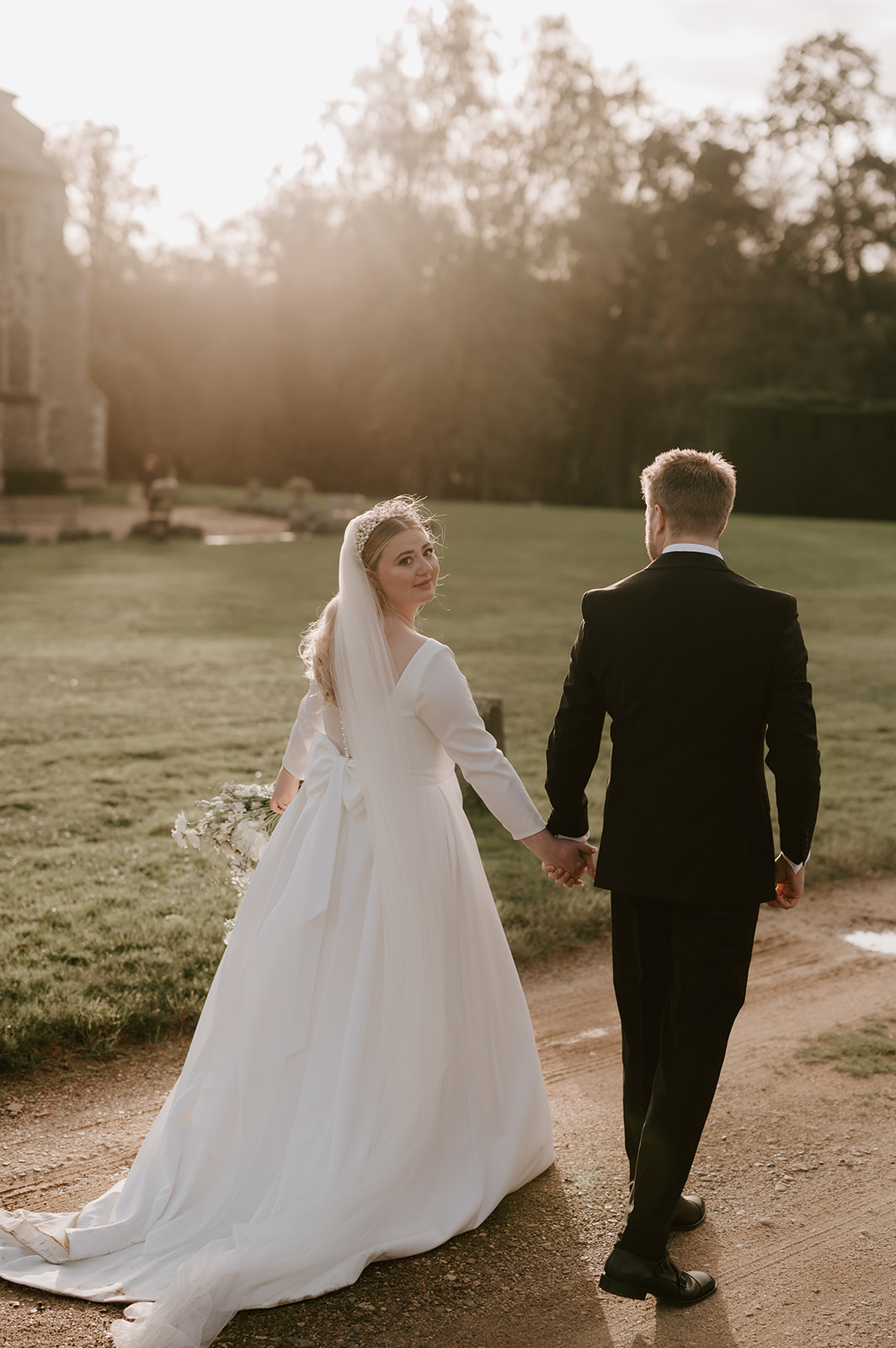 bride and groom walking away at golden hour at butley priory wedding