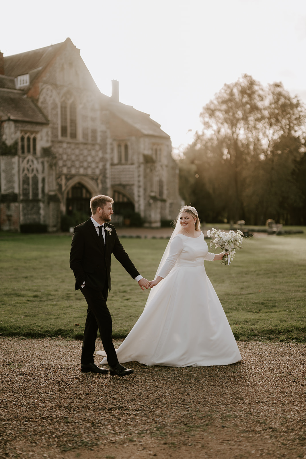 bride and groom walking at golden hour butley priory wedding