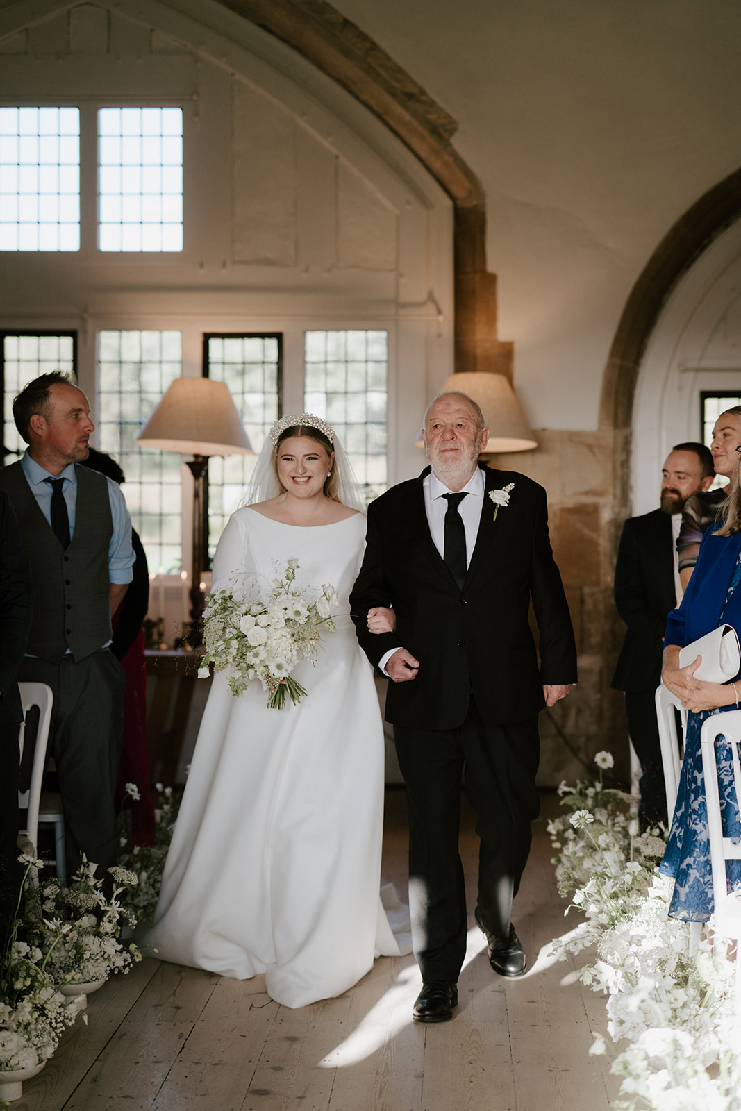 bride walking down aisle with father in great hall at butley priory