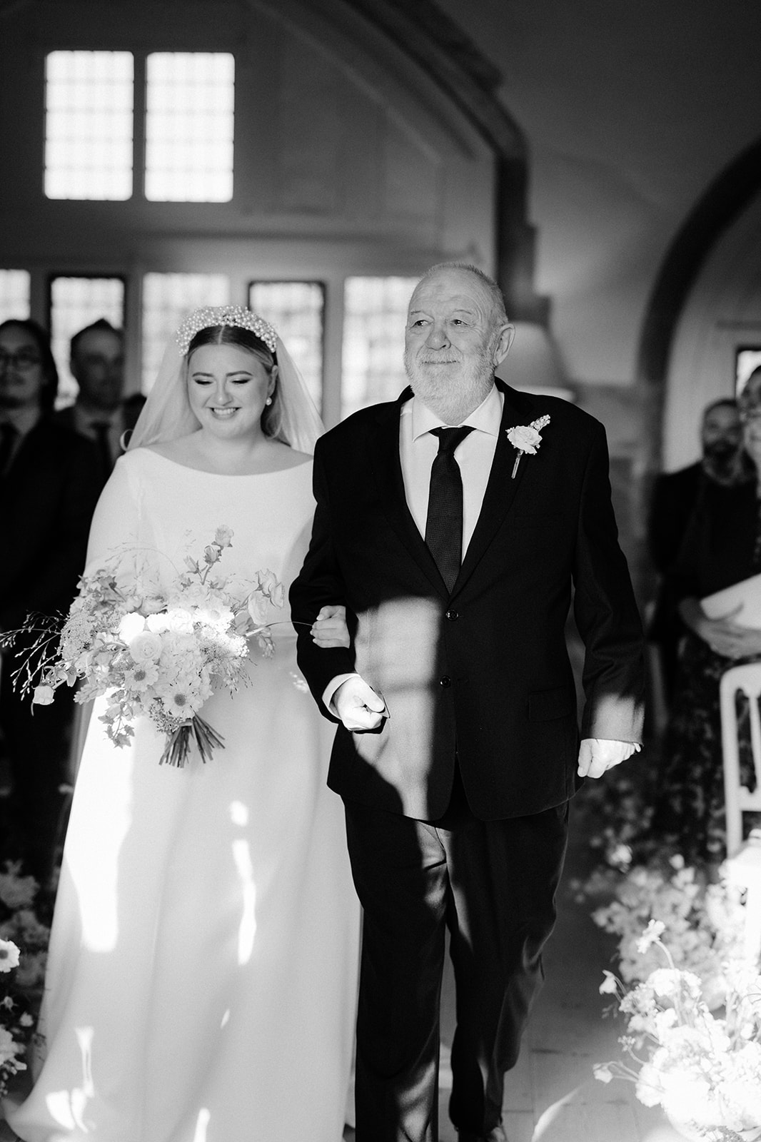 bride walking down aisle with father in great hall at butley priory