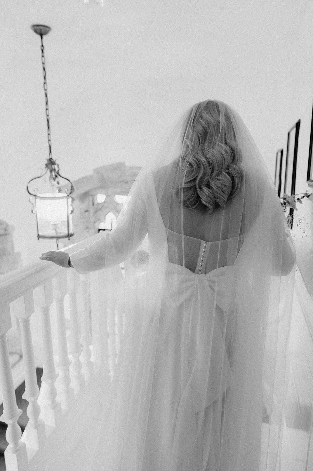 bride wearing veil walking down stairs at butley priory