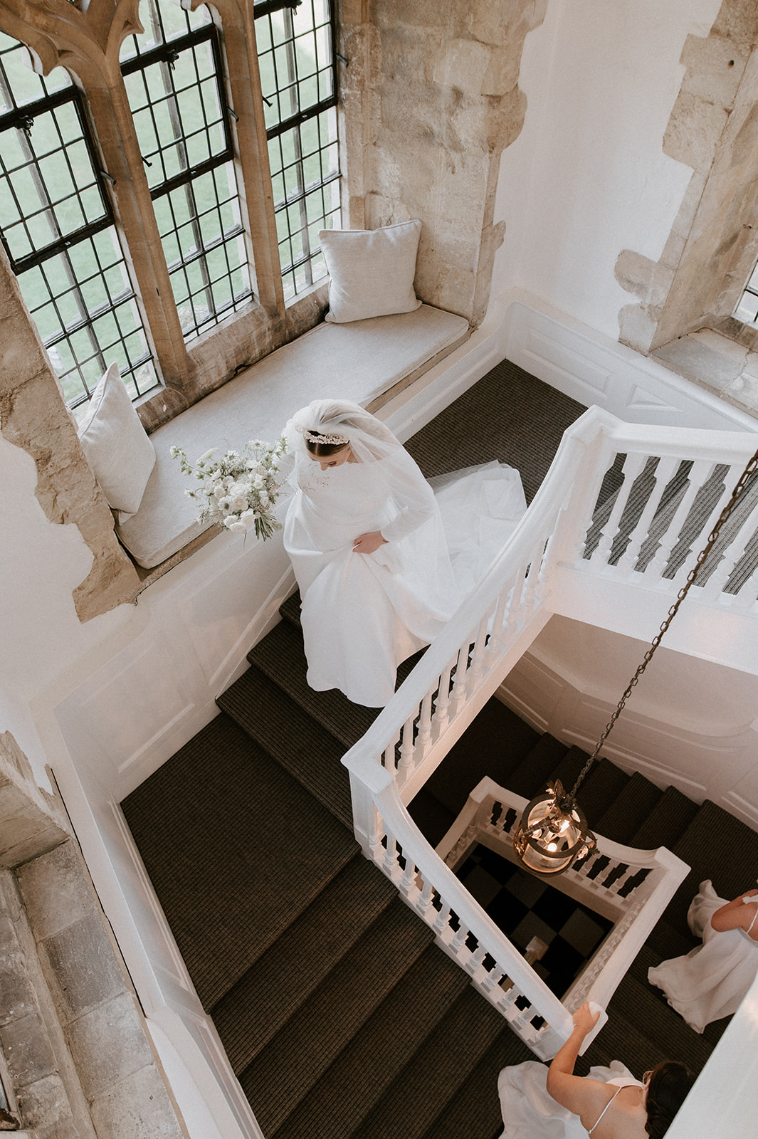 bride wearing veil walking down stairs at butley priory