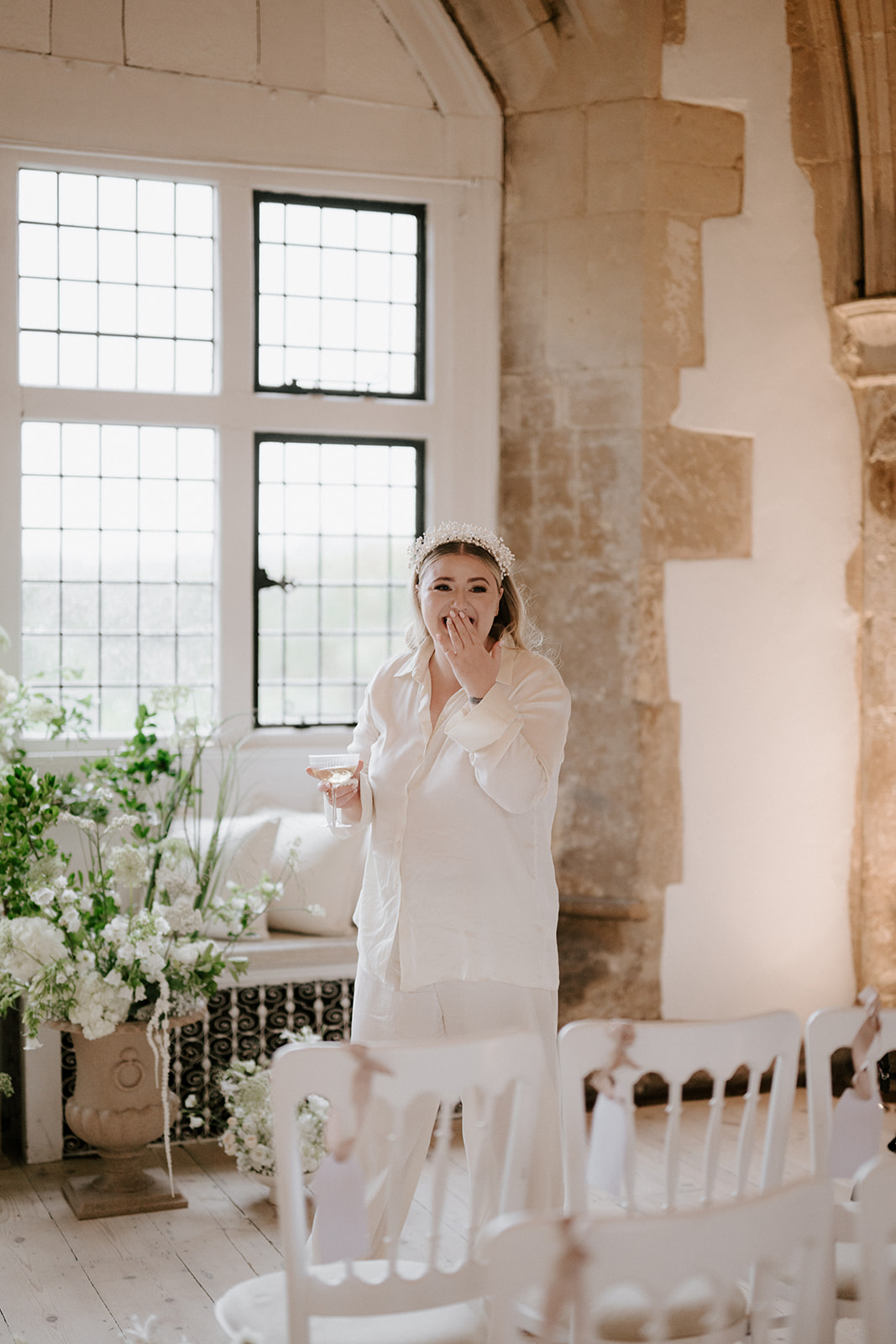 bride in white pjs smiling at ceremony set up in great hall at butley priory