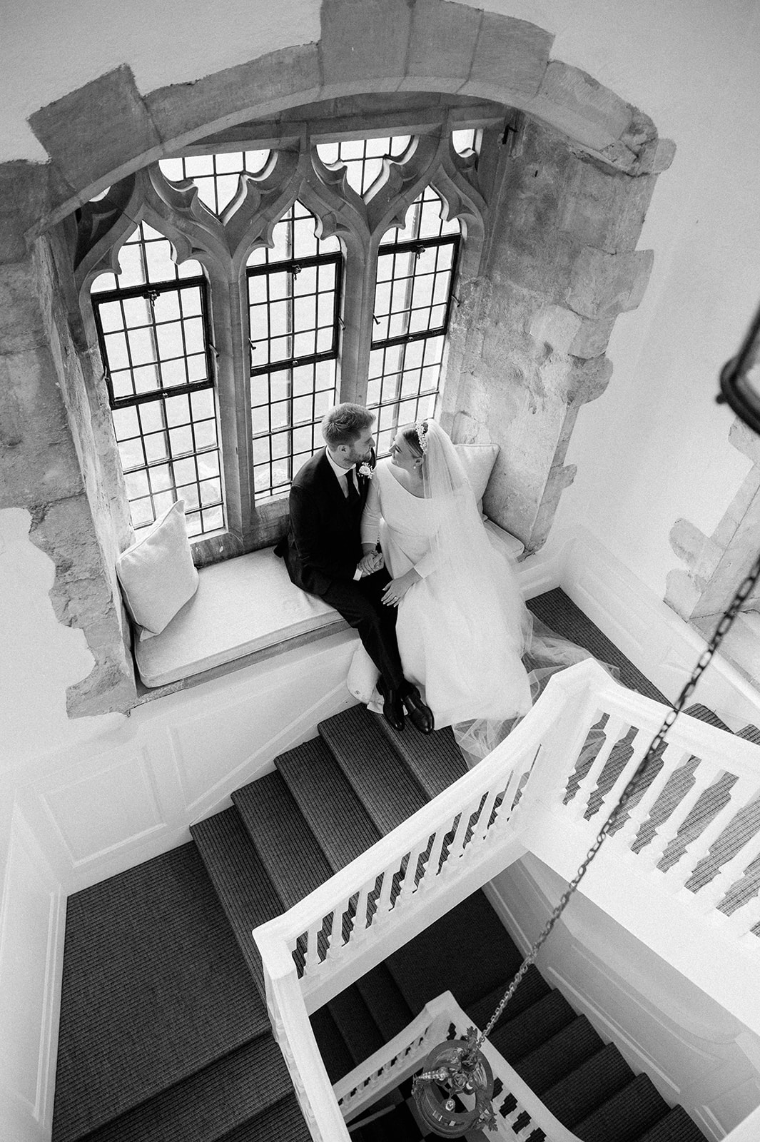 couple on window seat on stairs of butley priory Suffolk wedding venue
