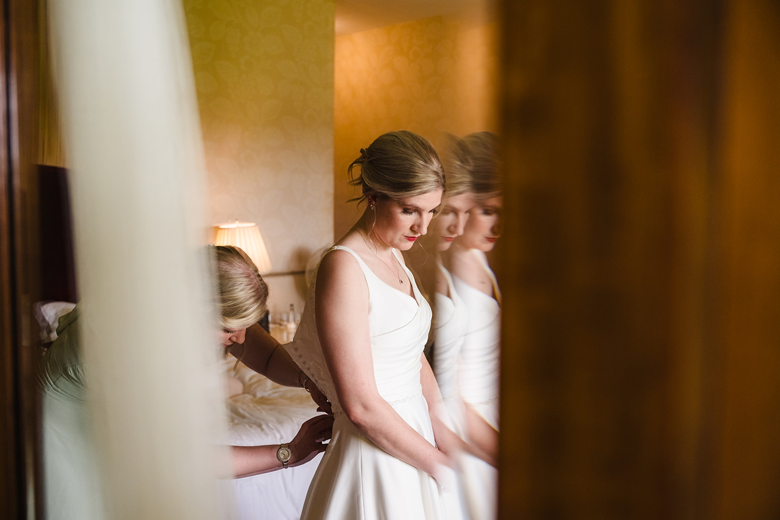 Brides sister helping her in to her dress at stapleford park by Amanda Forman Photography