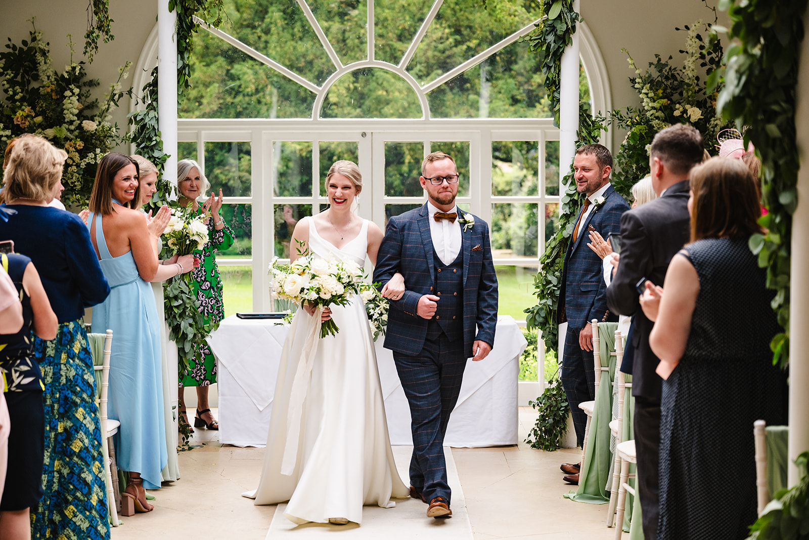 Bride and groom walking back down the aisle in the orangery at Stapleford Park hotel by Amanda Forman Photography
