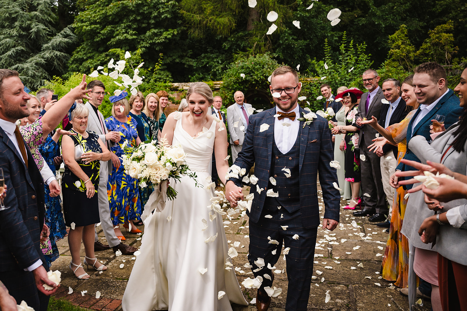 Bride and groom walking through confetti after their ceremony at stapleford park by Amanda Forman Photography