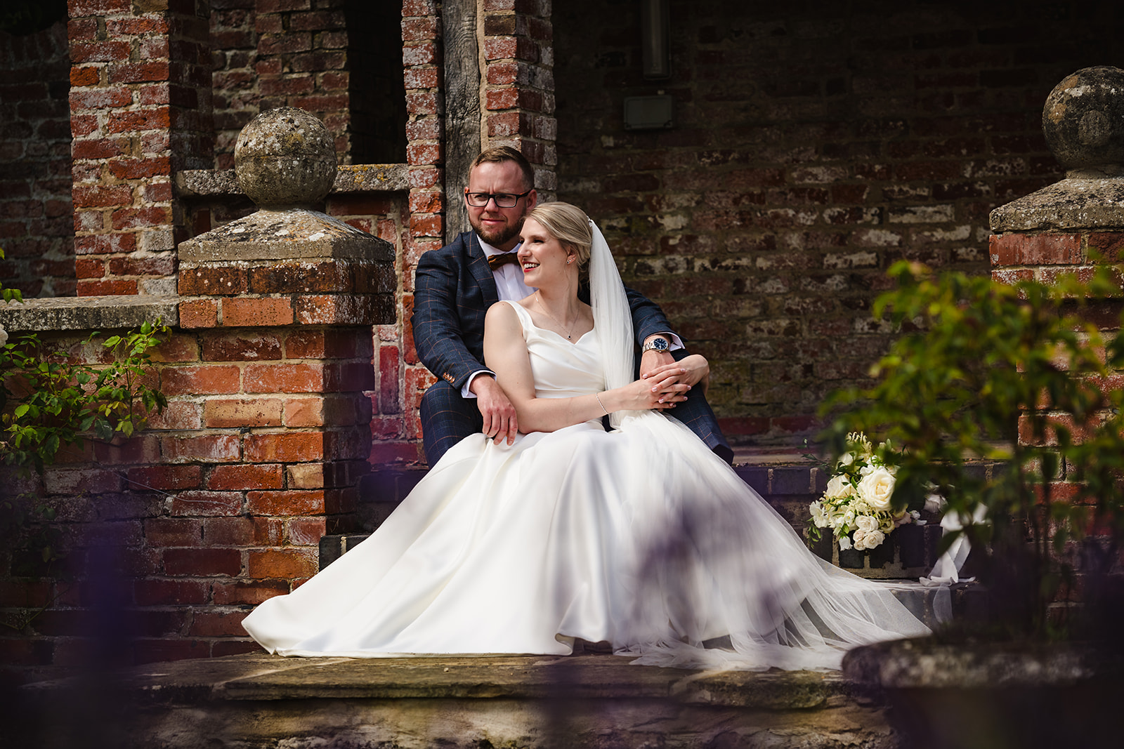 Bride and groom sitting on the steps in the gardens of Stapleford park by Amanda Forman Photography