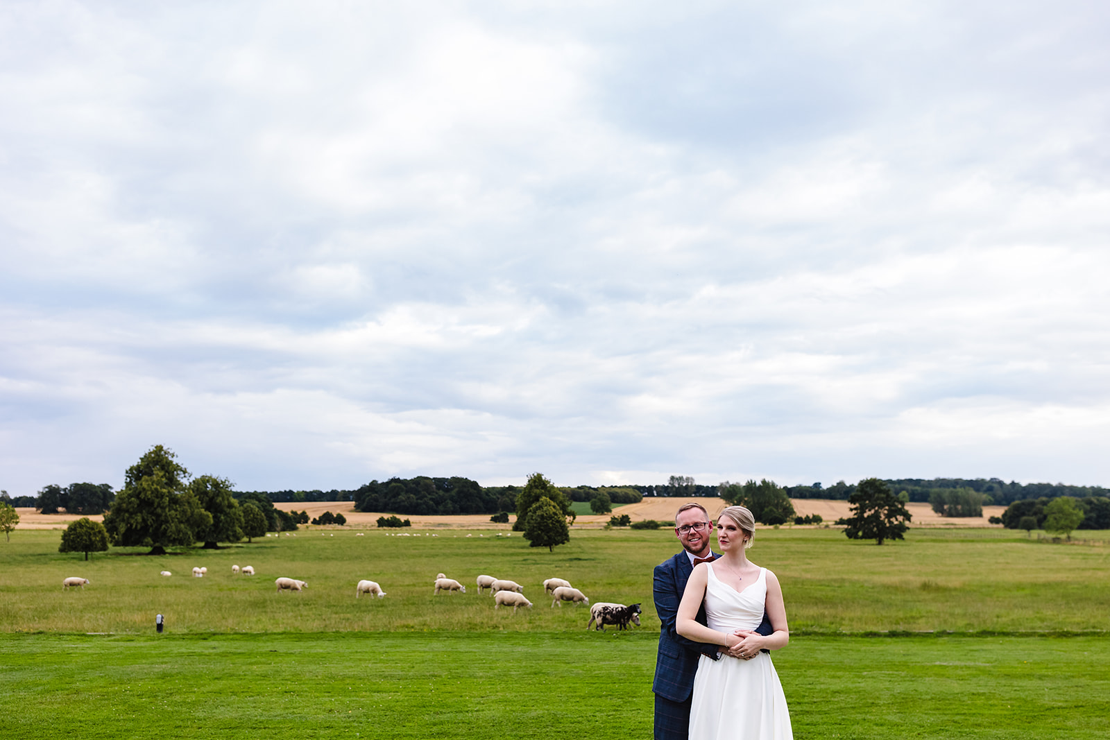 Bride and groom in the gardens at Stapleford park with a view out to the fields by Amanda Forman Photography