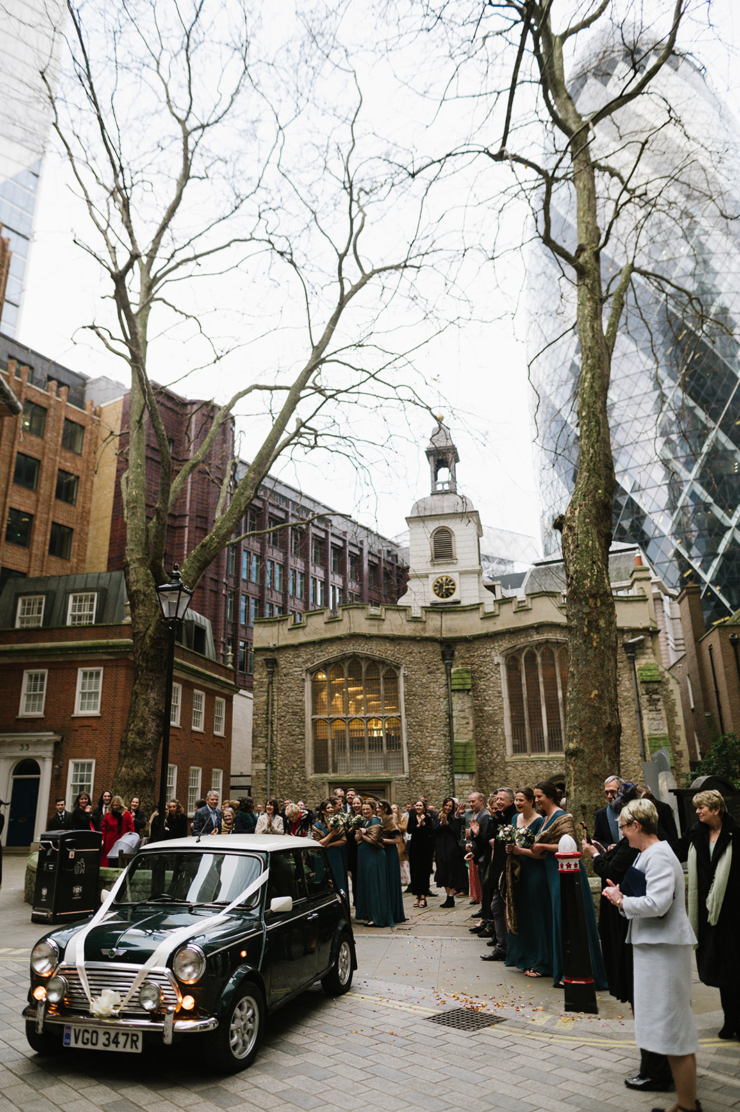 Bride and groom leaving their wedding in a Mini from St Helen's Church Bishopsgate, with the Gherkin in the background. 